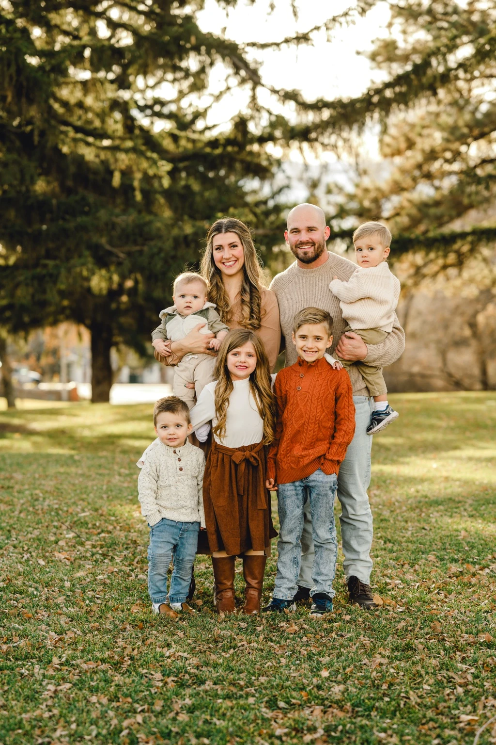 A family of seven together beneath sunlit autumn trees