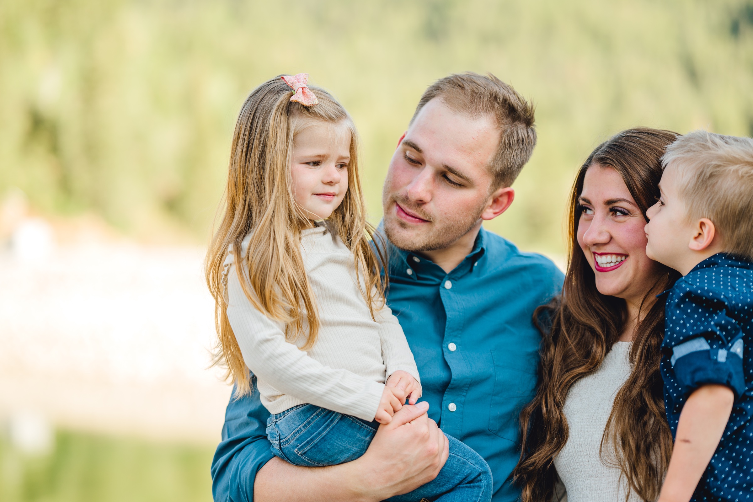 Parents holding their two children close in soft outdoor light
